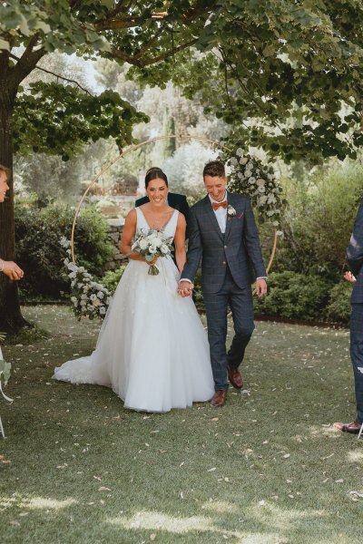 Bride and groom walking ceremony flowers