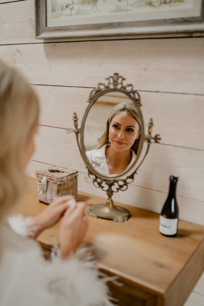 Bride looking into mirror bottle of champagne prosecco