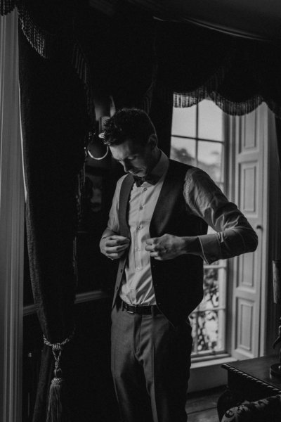 B&W groom getting ready in bedroom