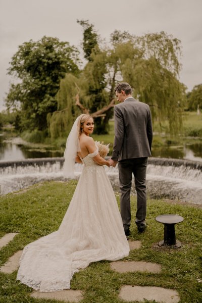 Couple after wedding ceremony bride groom bouquet flowers manor castle in background forest park lake fountain water