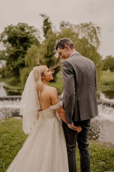 Couple after wedding ceremony bride groom bouquet flowers manor castle in background forest park lake fountain water