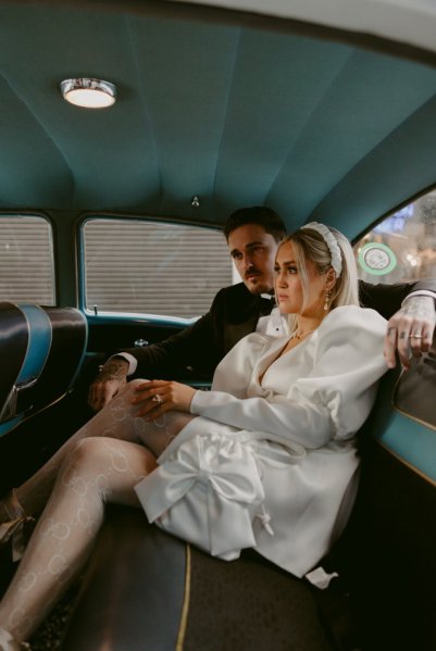 Bride and groom sitting in Cadillac wedding car