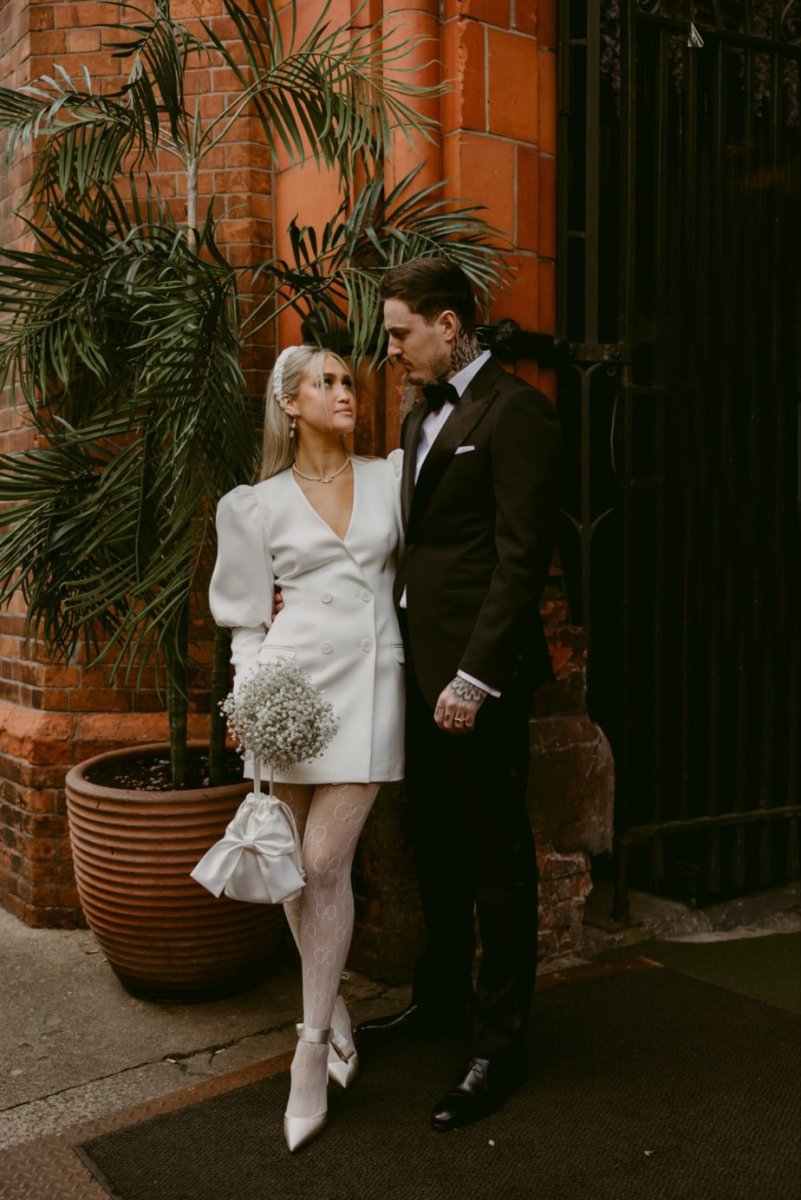 Exterior venue bride and groom white bag dress flowers