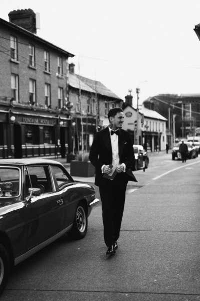 Groom beside wedding car on street