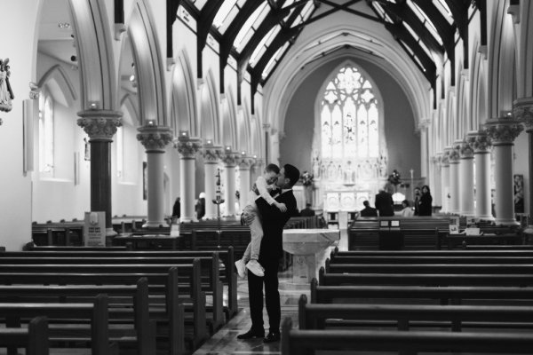 Groom holding up baby in church