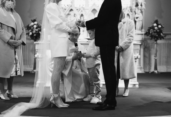 Priest and child holding ribbon for bride and groom to be bound at alter