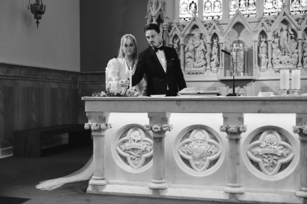 Bride and groom standing at alter lighting candle