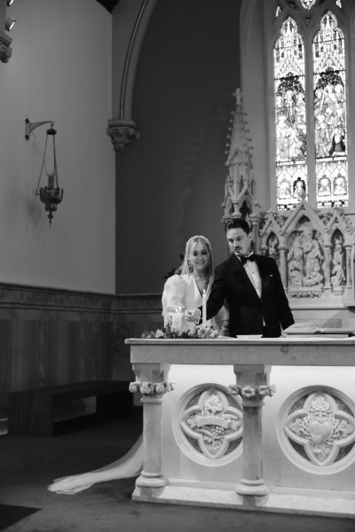 Bride and groom standing at alter lighting candle