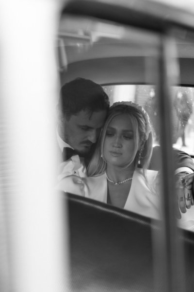 Bride and groom sitting in wedding car window view