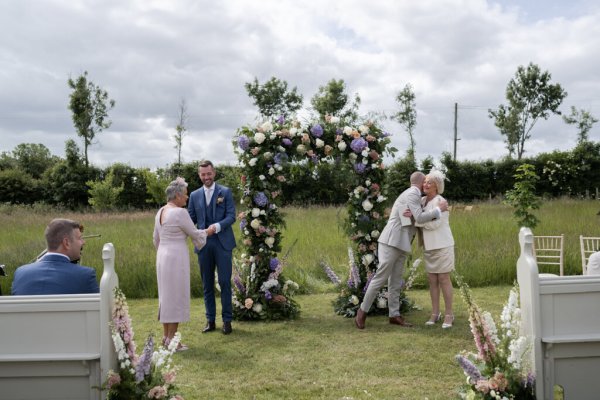 Grooms hug fathers wedding ceremony mothers