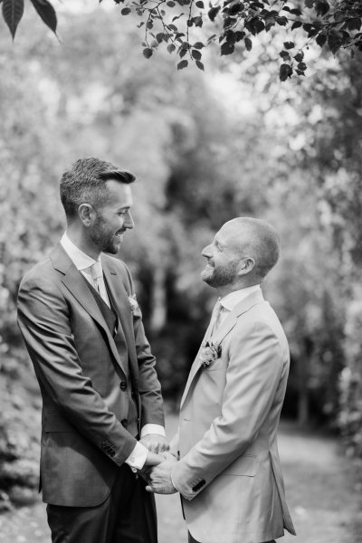 Grooms hand in hand in forest farm garden black and white