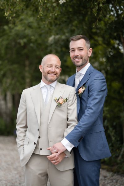 Grooms embrace hug in forest garden field