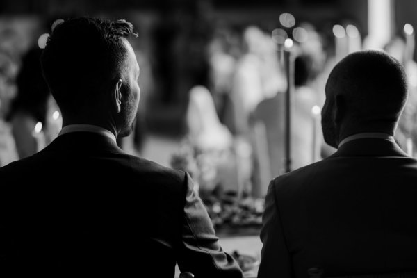 Black and white grooms during speeches dining room