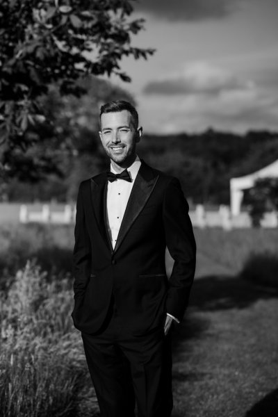 Groom wearing black suit and tie garden marquee