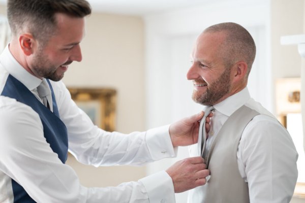 Groomsman helping groom get ready