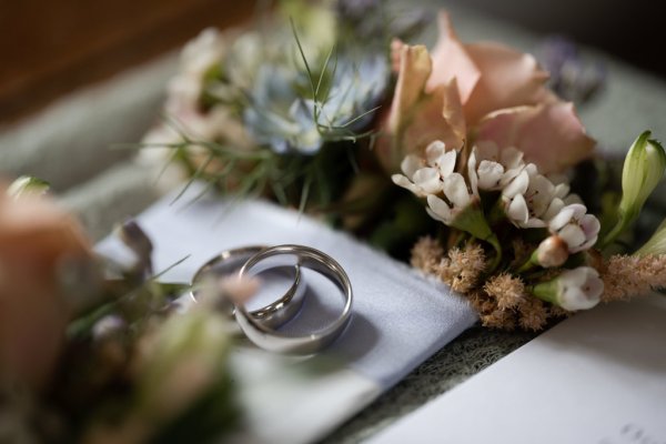 Close up of wedding band rings pink rose flowers