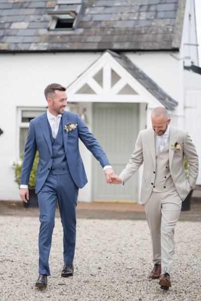 Smiling grooms hand in hand holding hands