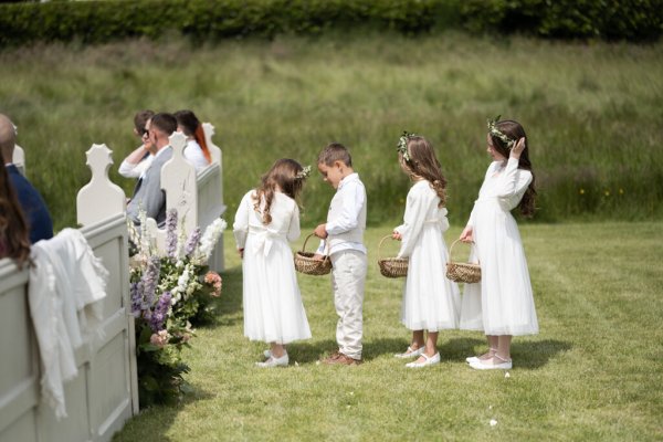 Flower girls and boys walking up aisle grass