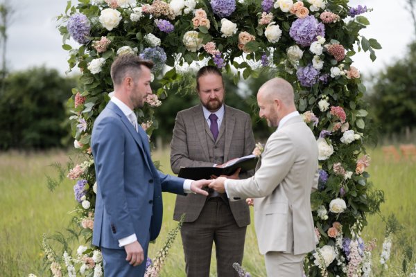 Grooms and officiant officiate wedding ceremony roses flower display