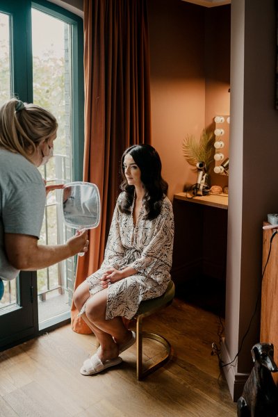 Bride looks at reflection in mirror hair