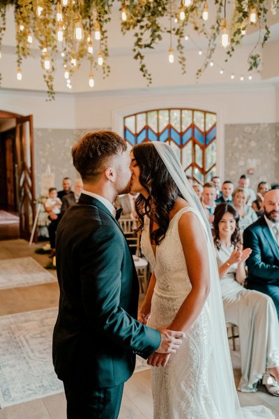 Bride and groom kiss during wedding ceremony