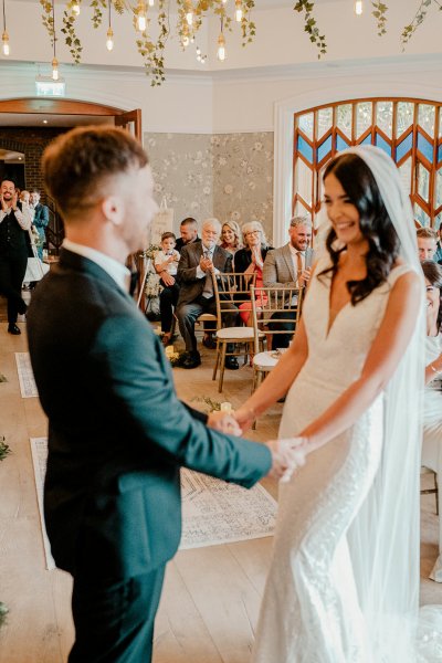 Bride and groom hand in hand holding hands during wedding ceremony