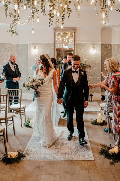 Bride and groom exiting wedding ceremony guests clapping