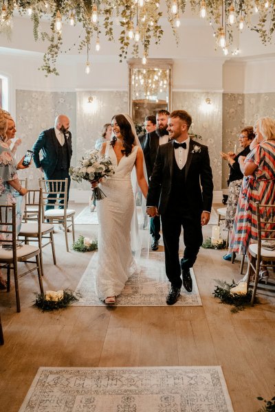 Bride and groom exiting wedding ceremony guests clapping