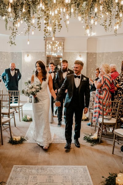 Bride and groom exiting wedding ceremony guests clapping