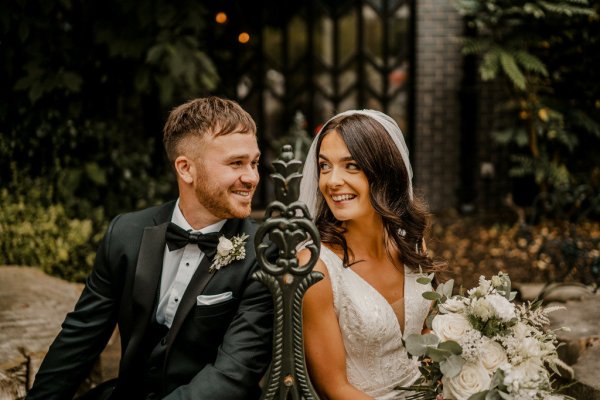 Bride and groom sitting on bench smiling