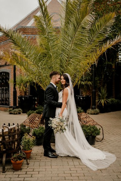 Bride looks at camera groom kisses cheek