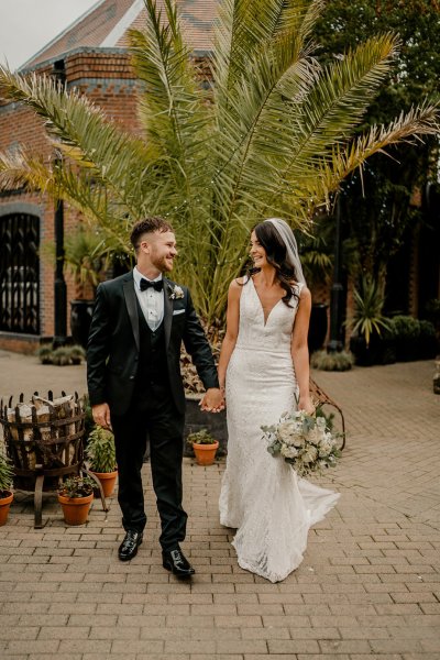 Bride and groom hold hands exterior shot