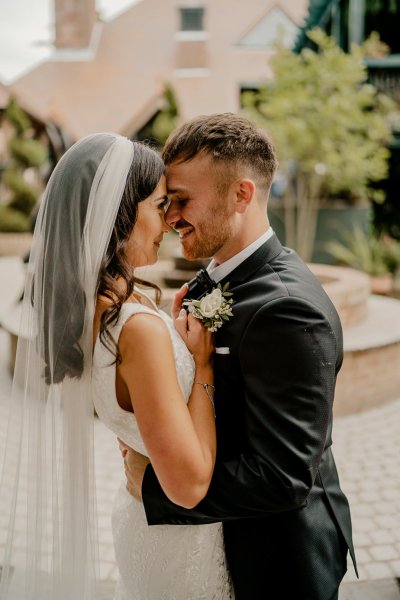 Bride wearing a veil groom hugs and embraces her