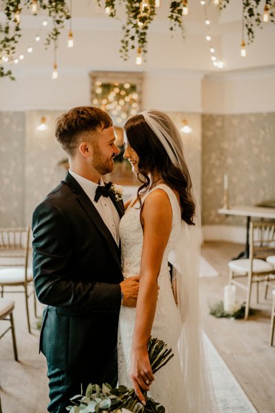 Bride and groom in empty wedding ceremony room looking at each other