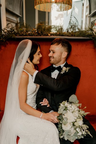 Bride and groom sit on regal red chair