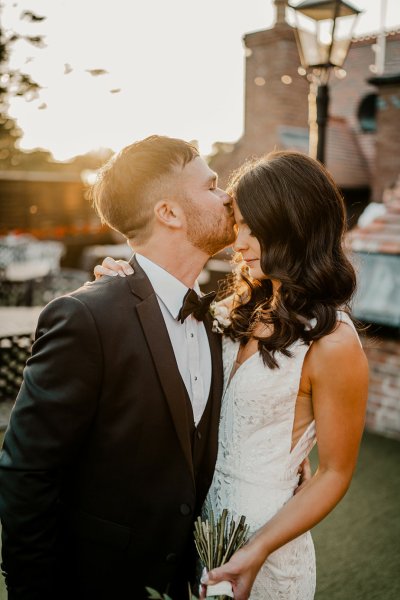 Groom kisses bride on forehead