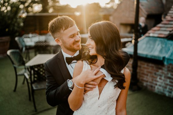 From behind the groom holds bride looks over shoulder