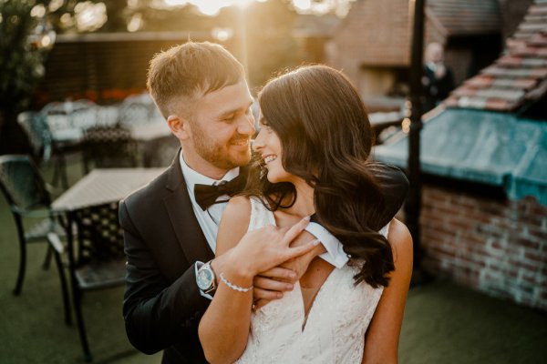 From behind the groom holds bride looks over shoulder