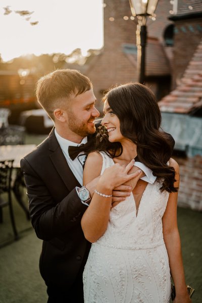 From behind the groom holds bride looks over shoulder