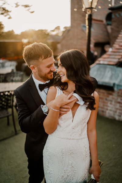 From behind the groom holds bride looks over shoulder