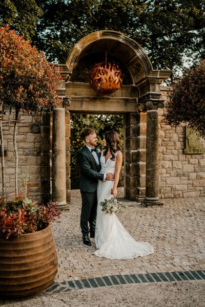 Bride and groom exterior autumn shot look at each other white flowers