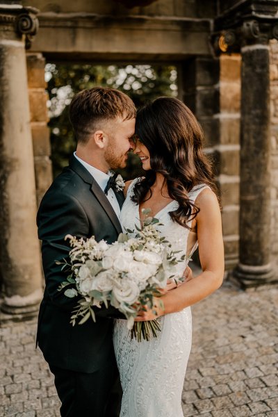 Bride and groom touch foreheads white flowers