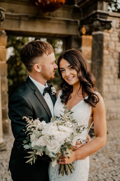 Groom kisses bride on forehead white flowers