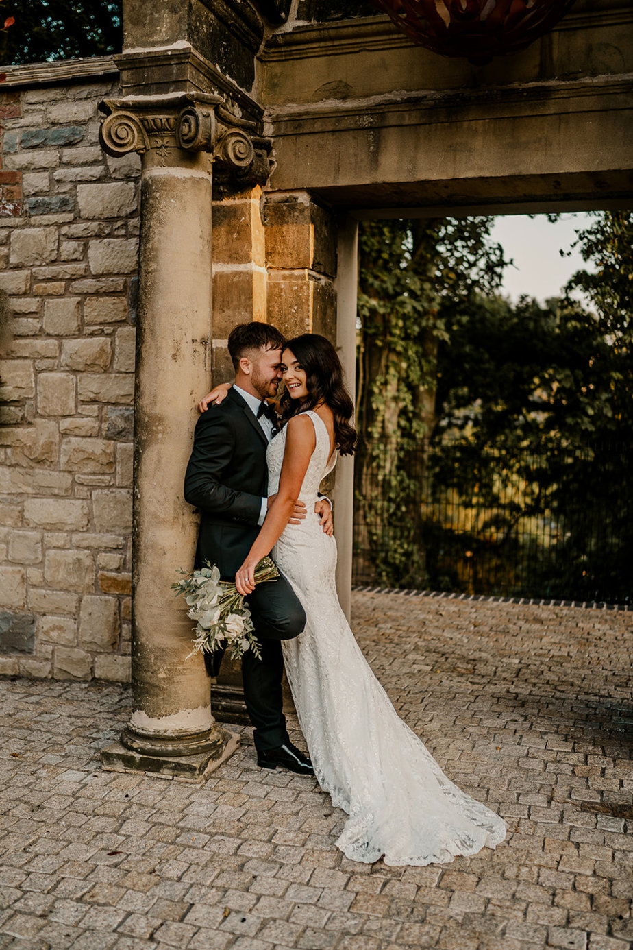 Bride and groom look at each other smile flowers in shot