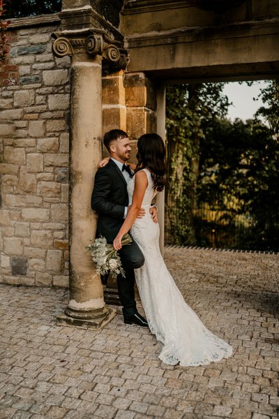 Bride and groom look at each other smile flowers in shot