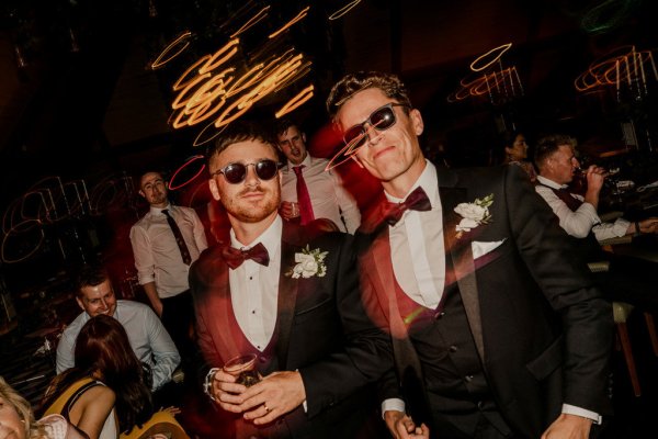 Groomsmen wear sunglasses inside suit and tie bow