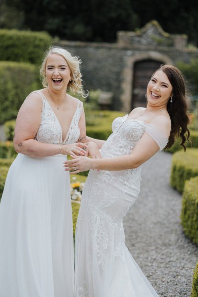 Brides in garden sunshine hug laugh flowers