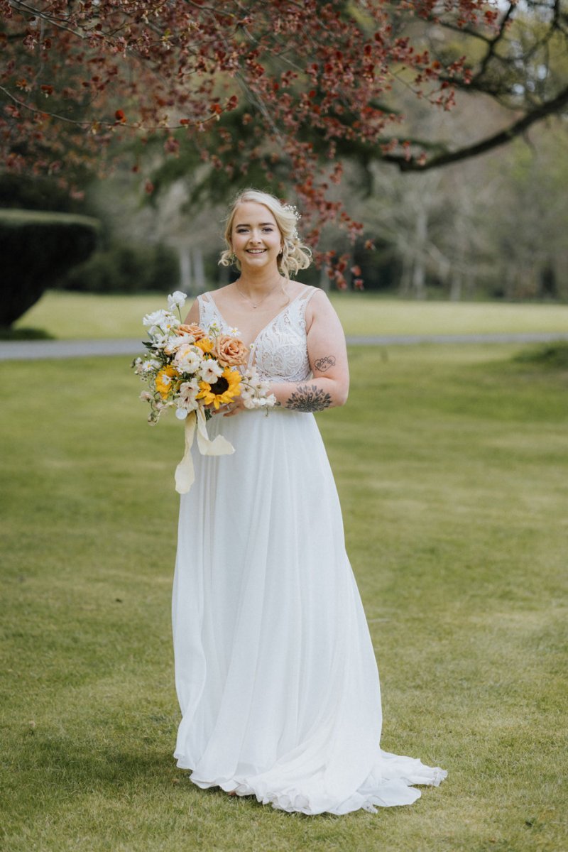 Bride holds sunflower flowers bouquet in field garden