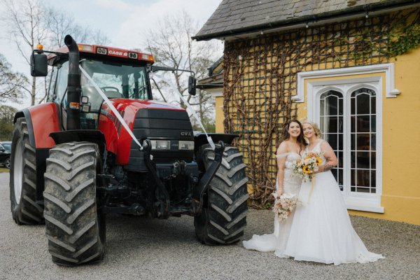 Brides wives red tractor with flowers on the wheel in front of venue