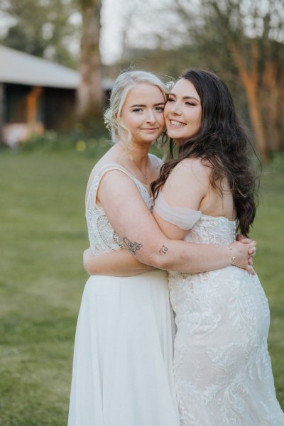 Brides hugging in field